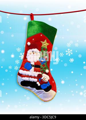 Christmas sock with Santa and tree decorations hanging on a snow flake background Stock Photo