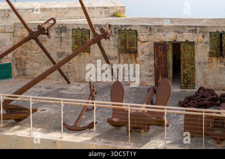Old anchors and chains rest on the ramparts of Fort Rinella in Malta. The fort was built by the British in the 1870s to protect the Grand Harbour. Stock Photo