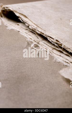 Closeup layered edge handmade mulberry paper sheet. Natural beige rough texture shows fibrous structure paper craft material. Stock Photo