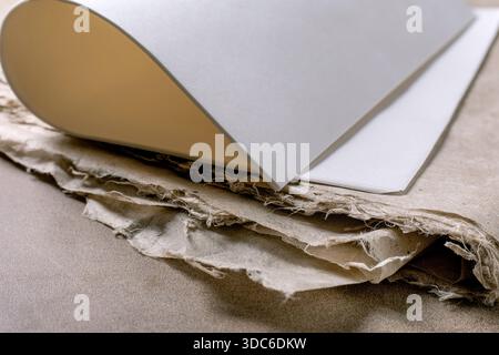 Close up white rice and mulberry paper sheets placed on textured handmade paper background. Natural materials workspace composition. Art supplies for Stock Photo