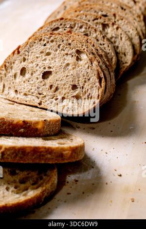 Freshly baked whole grain bread sliced on light background. Artisanal bread with porous texture crispy crust. Organic healthy baking. Stock Photo