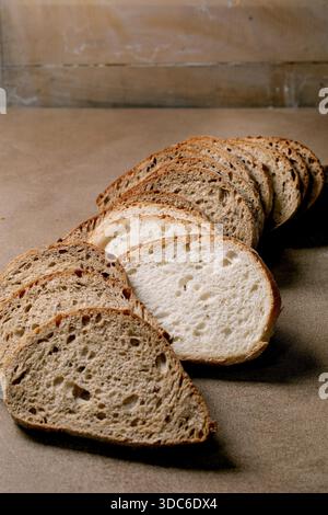 Fresh sliced artisan bread mixed varieties including white and multigrain loaf on brown wood. Rustic background with wooden texture. Stock Photo