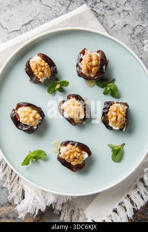 Close-up of dates stuffed with cream cheese, walnuts and honey in a plate on the table. Vertical top view from above Stock Photo