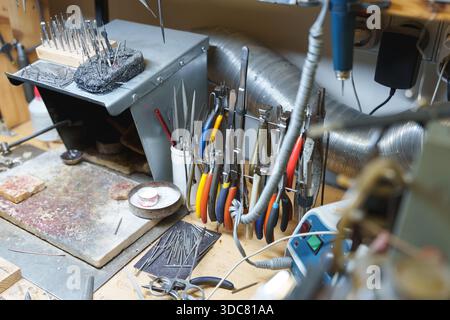 Various professional jewelry pliers and hand tools organized on a workshop workbench. High quality photo Stock Photo