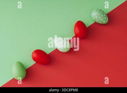 Spring composition with colored Easter eggs on green and red background. Creative Easter concept. Festive holiday layout. Flat lay. Stock Photo