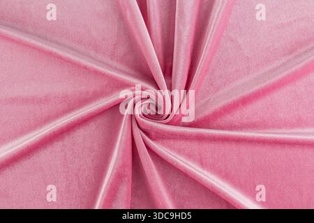 Chic velvet fabric in pink delicate color twisted in a spiral. elegant folds of soft velvet. layout for design, advertising of the product. top view. Stock Photo