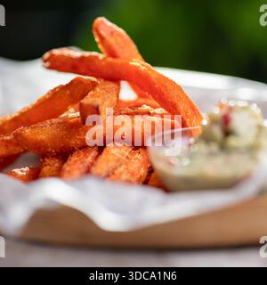 Baked sweet potato wedges with guacamole on a wooden plate, gray background. Vegan food concept. Stock Photo