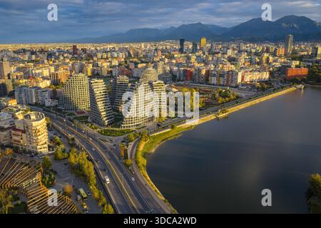 Golden hour aerial view over Tirana, showcasing Lake View Residences, the curving boulevard, and the dense urban landscape. Stock Photo