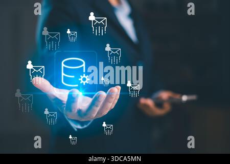 A business professional presenting glowing database icon with email user symbols, illustrating data processing, digital communication, cloud technolog Stock Photo