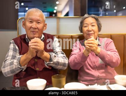 Happy Asian senior couple celebrating Chinese New Year in restaurant Stock Photo
