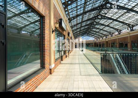 Interior of a modern shopping center with large glass roof, brick walls, and empty walkways. Beautiful architecture of a retail building Stock Photo