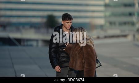 A young couple stands together on an urban street in Paris France sharing a moment of love and affection The woman wearing a stylish fur coat gently t Stock Photo