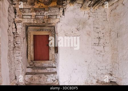 Small weathered monastery door set into thick stone wall at Hemis Monastery in Ladakh, India. Traditional Tibetan architecture Stock Photo