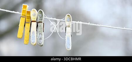 Frost on plastic clothes pegs left on a washing line in winter, banner form Stock Photo