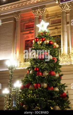 Beautiful decorated Christmas tree with red and golden balls in front of elegant historic building in center of Bucharest Stock Photo