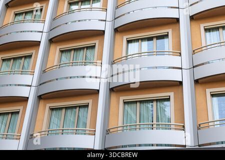 A contemporary residential building facade featuring curved balconies, beige walls, and large glass windows. This image captures urban living architec Stock Photo