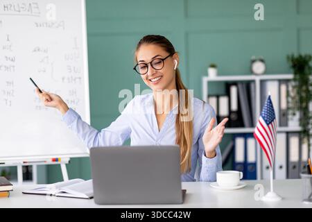 Young Teacher Engages Students in Online English Lesson From Home Office Stock Photo