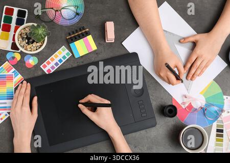 Female graphic designers working with tablet on dark background, top view Stock Photo