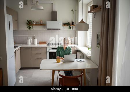 Smiling relaxed middle aged businesswoman fully immersed in working process, typing text on laptop. Stock Photo