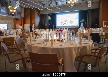 A tastefully furnished room with set tables and a large screen, Christmas party Dekra Congresshotel Wart, Calw district, Germany Stock Photo