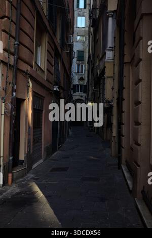 Street partially in the shade with the sky above framed by the tall buildings on the street itself and shutters of closed shops at street level Stock Photo