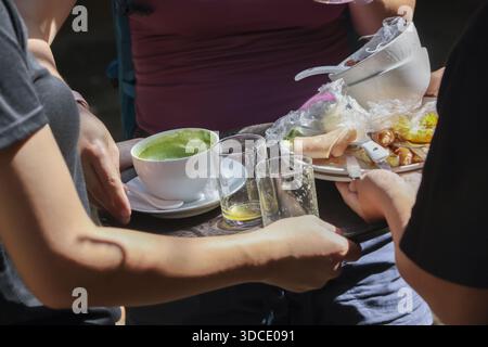 Close up waiter clearing dirty dishes and carrying tray with messy leftover food, empty glass and used napkin after lunch in busy restaurant showing h Stock Photo