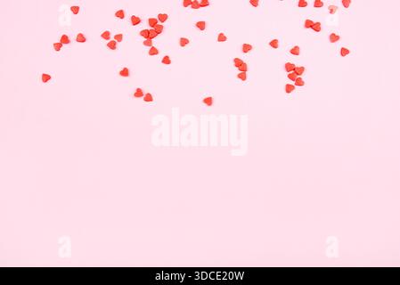 Tiny red hearts on pink background. Valentine's day concept. Top view. Stock Photo