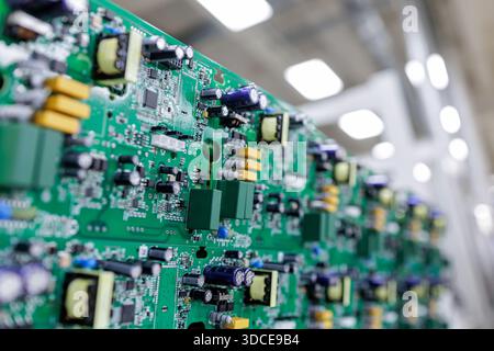 Detailed view of assembled green printed circuit board with power electronics components in modern factory Stock Photo