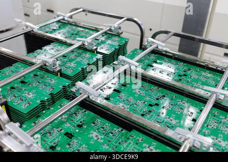 Stacks of green printed circuit boards clamped in metal racks inside modern automated electronics plant Stock Photo