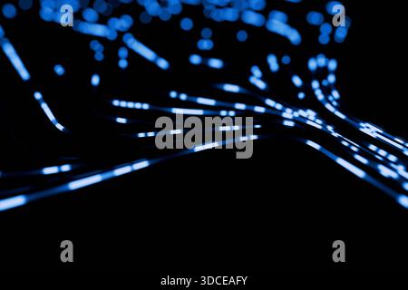 Abstract blue data streams and blurred light particles flowing dynamically across a black background. Concept for fast network, fiber optics, big data Stock Photo