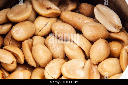 Macro shot of a scattering of roasted peanut halves with salt. The dense texture of these popular nuts, the concept of a healthy snack, protein. Stock Photo