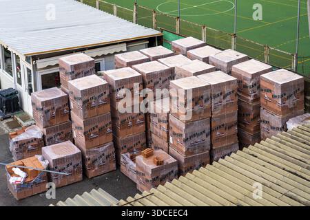 Genoa, Italy - 27 December 2022: View of stacked bricks wrapped in plastic sit in the harsh light, contrasting with the green artificial turf of a spo Stock Photo