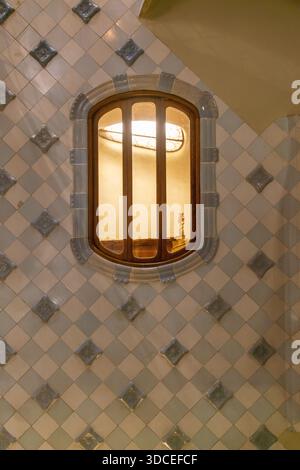 Barcelona, Spain - 06 November 2016: View of a quaint window framed by patterned tiles, casting a warm glow against the cool ceramic backdrop. Stock Photo