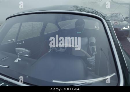 humanoid robot drives a vintage car on a foggy road, symbolizing the future of autonomous driving, artificial intelligence, and advanced automotive te Stock Photo