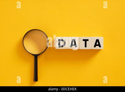 Wooden cubes displaying the word data alongside a magnifying glass. Data analysis and research concept. Stock Photo