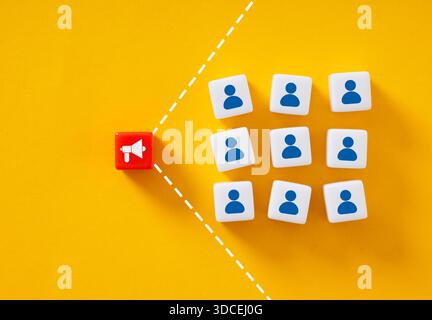 Red dice with megaphone icon promoting to target audience represented by blue people icons on white dice over yellow background Stock Photo