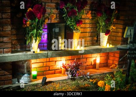 Santa Maria del Tule, Mexico - 03 November 2023: View of vibrant marigolds and deep red flowers contrasting against the rough brickwork and flickering Stock Photo