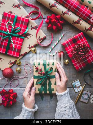 Overhead of hands wrapping many presents for Christmas. Stock Photo