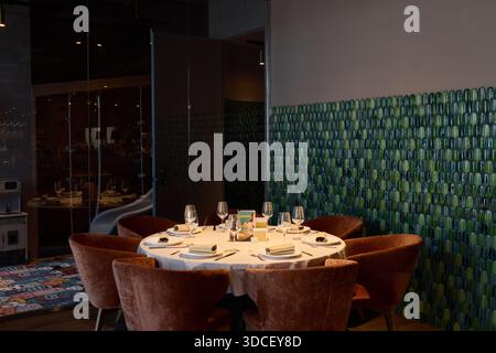Round table set for dining in a modern restaurant space Stock Photo