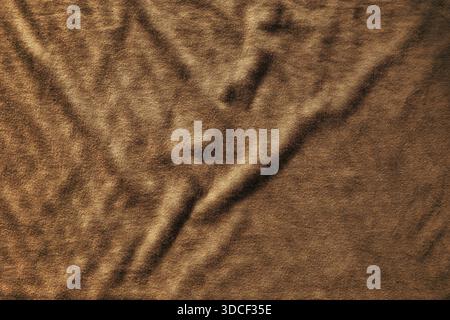 Wrinkled brown fabric texture with soft folds and natural shadows, creating an organic textile surface ideal for backgrounds, patterns, and design ele Stock Photo