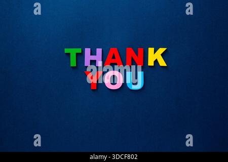 Colored wooden alphabet letters spelling out thank you on a dark blue surface Stock Photo