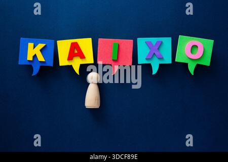 Wooden peg doll communicating kaixo with colorful speech bubbles on a dark background Stock Photo