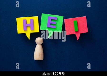 Wooden figure having a conversation with hei word in speech bubbles on blue Stock Photo