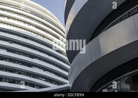 View of striking modern architecture with curved white panels against a bright blue sky, creating a dynamic contrast in Beijing, China Stock Photo