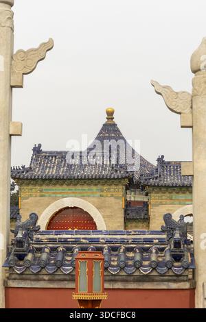 View of the vibrant blue-tiled roofs, ornate details, and golden accents of a traditional Chinese building, framed by stone pillars, Beijing, Beijing, Stock Photo