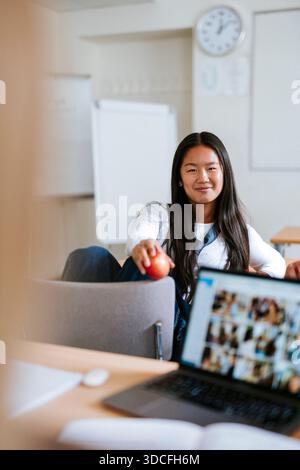 Portrait of smiling long haired young female student sitting in university classroom Stock Photo