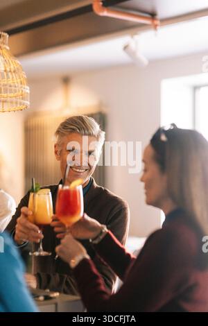 Smiling man toasting cocktail with female friend in party at bar Stock Photo