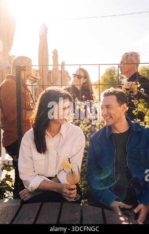 Happy mature friends talking with each other while sitting outdoors in cocktail party Stock Photo
