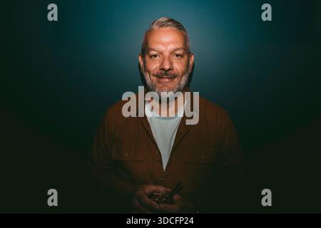 Portrait of smiling mature man against wall at nightclub Stock Photo