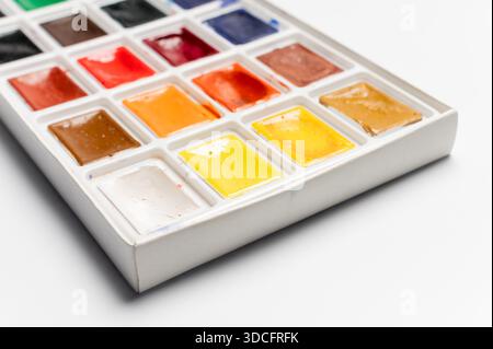 Watercolor packaging on a white background, side view from above. New paints have been opened for new work and painting. No one is in the photo, a close-up of the professional paints. Stock Photo